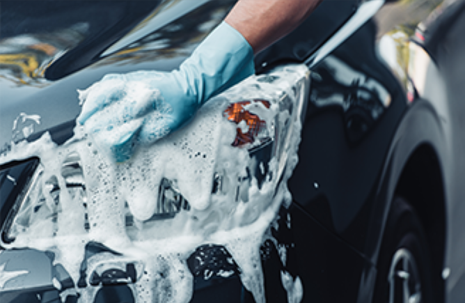 Gros plan sur le lavage d'une voiture noire avec de la mousse de savon.